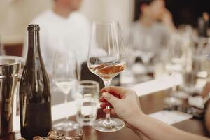 Glasses with different types of wine and human hands holding wine glasses in the background photo