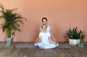 Smiling mother and daughter practicing yoga together photo
