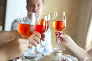 Closeup of four glasses with rose wine being clinked together photo