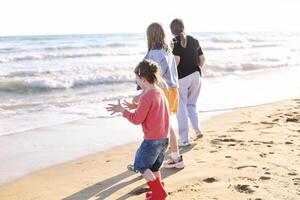 Joyful happy family mother and two daughters standing on seashore looking at surf and waves photo