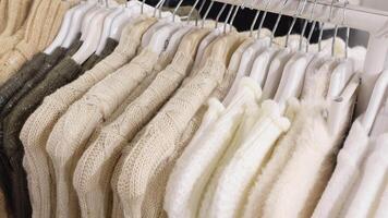 A Collection of Neutral Colored Knitted Sweaters Hanging on Display Rack in a Fashion Store video