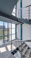 vertical loop rotation and panoramic view on emergency stairs in empty modern hall with columns, doors and panoramic windows overlooking the city. video