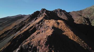 Aerial view, climbing to the top of the mountain preparing for a dive from the upper ridge, alpine sunny landscape. Sports drone with first person view, epic rocky landscape. video