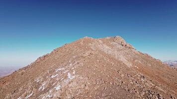 Aerial view, climbing to the top of the mountain preparing for a dive from the upper ridge, alpine sunny landscape. Sports drone with first person view, epic rocky landscape. video