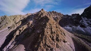 A soaring climb up an epic rock high in the mountains covered in snow on a sunny day. The footage was shot on a sports FPV drone quadcopter. Close spans with rocks video