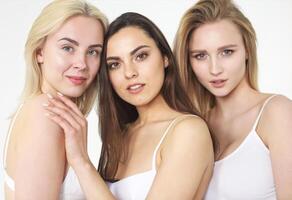 Group of happy different women in white hugging over white background. photo