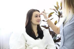 Aesthetic cosmetology. Facelift in spa salon. Beautician makes markup for injection. Smoothing of mimic wrinkles photo