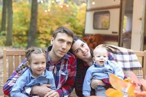 Portrait of a young smiling family while hugging near house on wheels photo