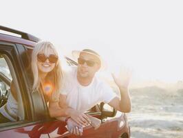 Young stylish couple in sunglasses hugging near red car photo