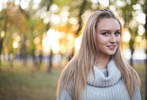 Happy girl posing in autumn park on yellow trees background photo
