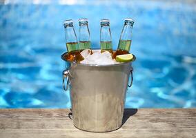 Closeup view of bucket with ice cubes, beer bottles and lime slices photo