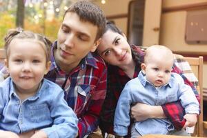 Portrait of a young smiling family while hugging near house on wheels photo