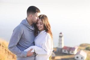 Romantic couple dressed in cozy sweaters together near the lighthouse photo