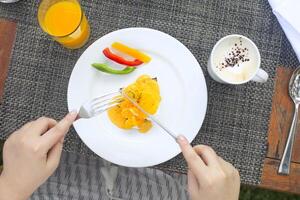 Cropped image of person eating eggs benedict at a cafe table photo