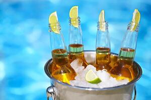 Closeup view of bucket with ice cubes, beer bottles and lime slices photo