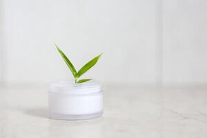 Face cream with bamboo leaves over light background photo