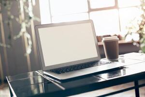Blank screen of laptop with keyboard case lying on little black table photo