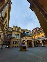 A view of a historic courtyard with elegant architecture illuminated by warm lights at dusk. The image captures the intricate details of the buildings, showcasing the blend of old-world charm and architectural beauty. photo