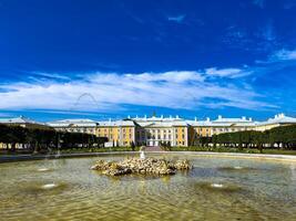 A stunning view of a majestic palace with an elegant fountain in the foreground and a clear blue sky, showcasing the grandeur and beauty of historic architecture on a sunny day photo