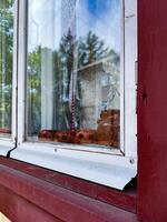 A close-up view of a rustic window adorned with clay figurines and delicate lace curtains, offering a glimpse into a cozy, traditional home atmosphere photo