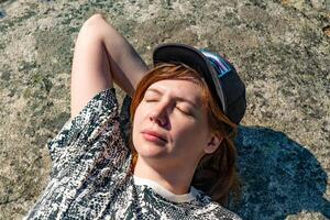 Close-up of a woman relaxing and smiling in a sunlit forest, showcasing her joy and serenity amidst nature. Ideal for themes of relaxation, nature, and outdoor lifestyle. photo