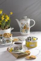 Still life with Kusmi tea and milk cookies on a table, vase with yellow spring daffodils, As, Belgium, February 23, 2021 photo