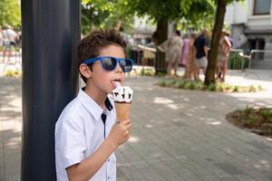 Cute child boy with a dirty face eats ice cream, the child enjoys dessert, walk in the park, High quality photo