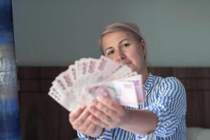 woman holds large stack of 200 Turkish lira bills in front of her, spreads it with a fan and shows it to the camera, a lot of money, but little value, high inflation in Turkey,money out of focus photo