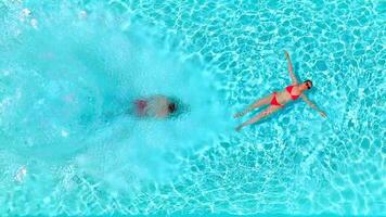 Top down view as a man dives into the pool while woman lays on her back video