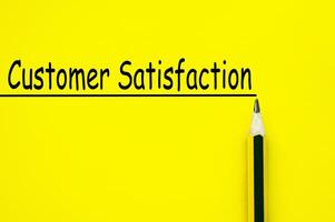 Customer satisfaction text written on yellow paper background. Customer focus concept. photo