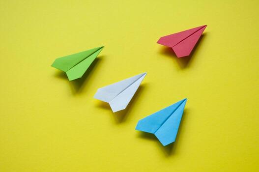 Top view of multicolored paper airplane on yellow background representing diversity and inclusion photo
