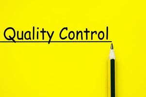 Quality control text written on yellow paper background photo