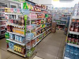 Aisle with various kinds of goods on the shelves inside Alfamart ,one of Indonesia local franchice Mini market business unit. selective Focus image. Bandung-Indonesia,February 27 2024 photo