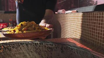 The chef puts carrots with a slotted spoon in a plate with rice from a large cauldron for pilaf video