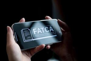 FATCA, Foreign Account Tax Compliance Act. Checking information with applications on smartphone for United States law for financial institutions Non-American citizens report financial and taxes. photo