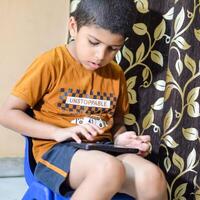 Portrait of Asian smart happy little boy using Mobile phone at home. Little boy holding mobile smart phone, online back to school concept. Online Class concept photo