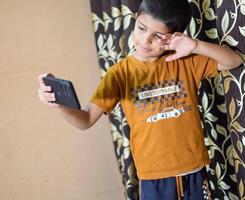 Portrait of Asian smart happy little boy using Mobile phone at home. Little boy holding mobile smart phone, online back to school concept. Online Class concept photo