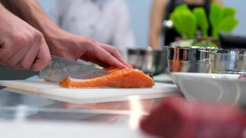 Cooking salmon steak grilling fillet salmon with asparagus, tomato, lemon. A chef's hand is squeezing a fresh lemon over a peace of red sea fish. Cooking process. Slow motion. close up video