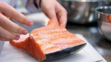 Cooking salmon steak grilling fillet salmon with asparagus, tomato, lemon. A chef's hand is squeezing a fresh lemon over a peace of red sea fish. Cooking process. Slow motion. close up video