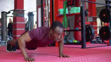 Handsome young Black man struggling with doing push-ups on gym floor video