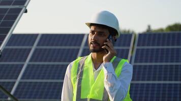 Professional Asian worker wearing safety helmet, holding mobile phone, making a call. Engineer, worker, or architect working with Solar roof concept video