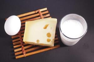 Various dairy items such as cheese, milk, and eggs displayed on a wooden table mat photo