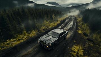 Aerial view of black SUV speeding on muddy mountain road photo. FPV drone shot image background wallpaper. Misty coniferous forest photography. Adventure exploration concept picture photo