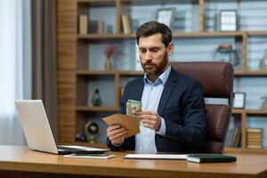A focused mature businessman wearing a suit intently works in a home office setting, managing bills or finances. photo