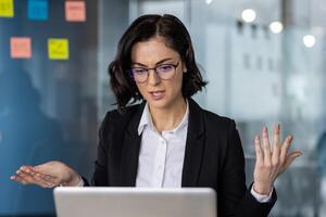 Businesswoman in office with confused expression during call. Concept of workplace frustration, communication issues, remote work challenges. Professional setting with sticky notes background. photo