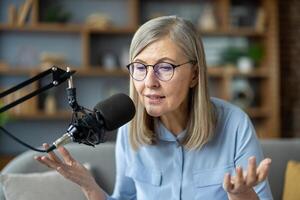 Senior woman records podcast at home, speaking into microphone. She discusses various topics, sharing knowledge and insights. photo
