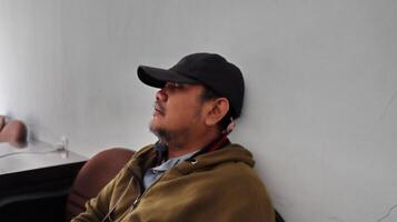 an adult man leeping exhaustedly leaning against the wall photo