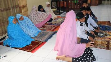 Small child learning to pray is taught directly by the teacher photo