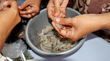 Hands peeling shrimps, preparing for cooking photo