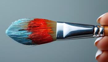 Hand holding a paintbrush as concept for art class and other creative endeavours. Colourful paintbrush with paint strokes on simple white background for art class. Painting photo